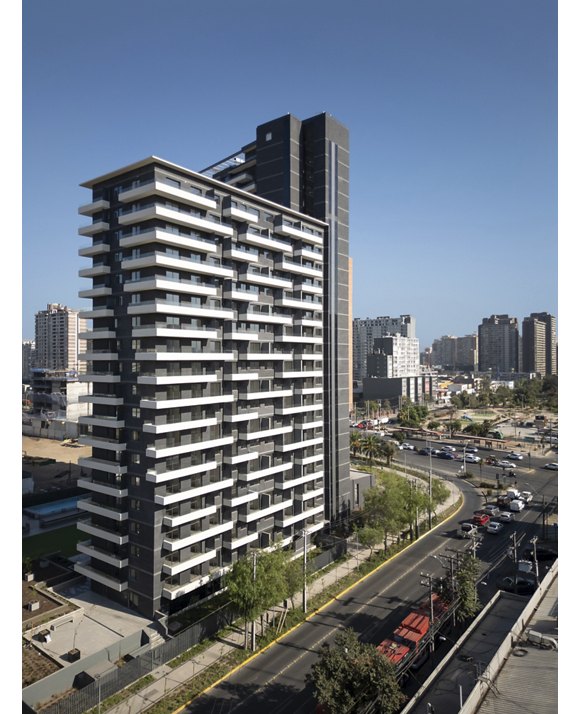 Tall, modern apartment building along a city street with a clear blue sky.