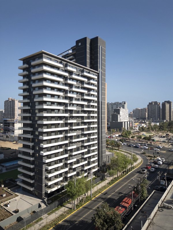 Tall, modern apartment building along a city street with a clear blue sky.