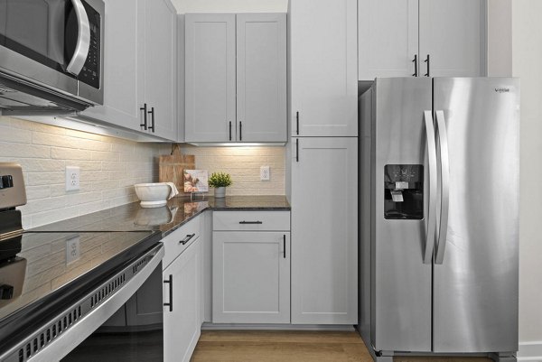 Kitchen with modern appliances and granite countertops at Flats at General Time Apartments