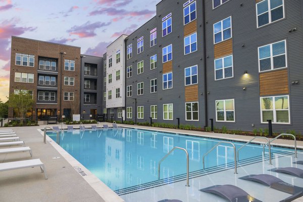 Relaxing pool area at Flats at General Time Apartments with comfortable lounge chairs and lush landscaping, ideal for unwinding outdoors