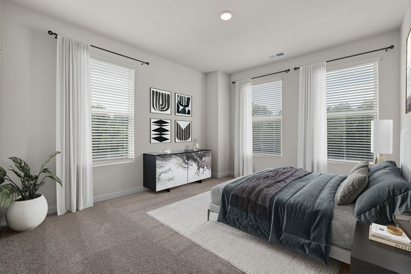 Elegant bedroom featuring modern furnishings and large windows at Gladwen Wendell Falls Apartments