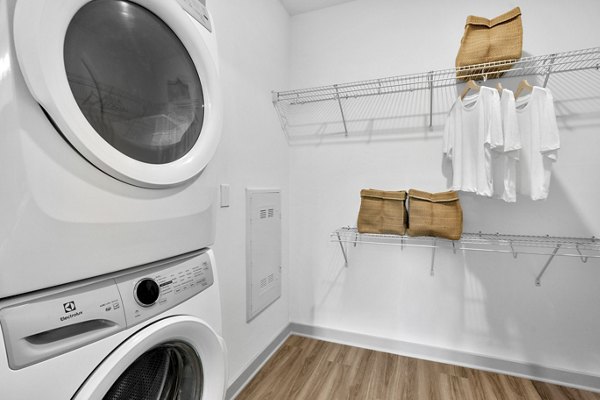 Laundry room with modern appliances at Alexan Research Park luxury apartments