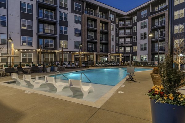 Modern pool area at Alexan Research Park Apartments featuring sun loungers and landscaped gardens