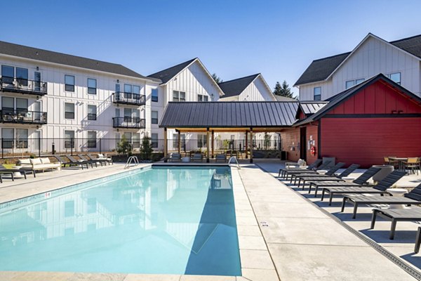 Relaxing outdoor pool area at The Farmstead Apartments, perfect for leisurely swims and sunbathing