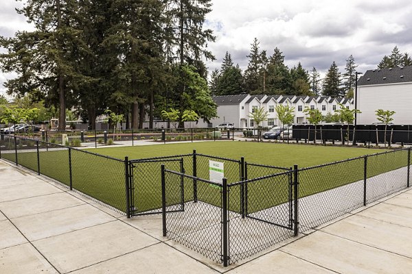 Dog park with agility equipment at The Farmstead Apartments offering fun and exercise options for pet owners and their furry friends