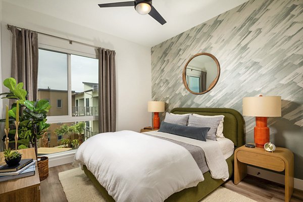 Triton Encinitas Apartments: Cozy bedroom featuring plush bedding and natural light