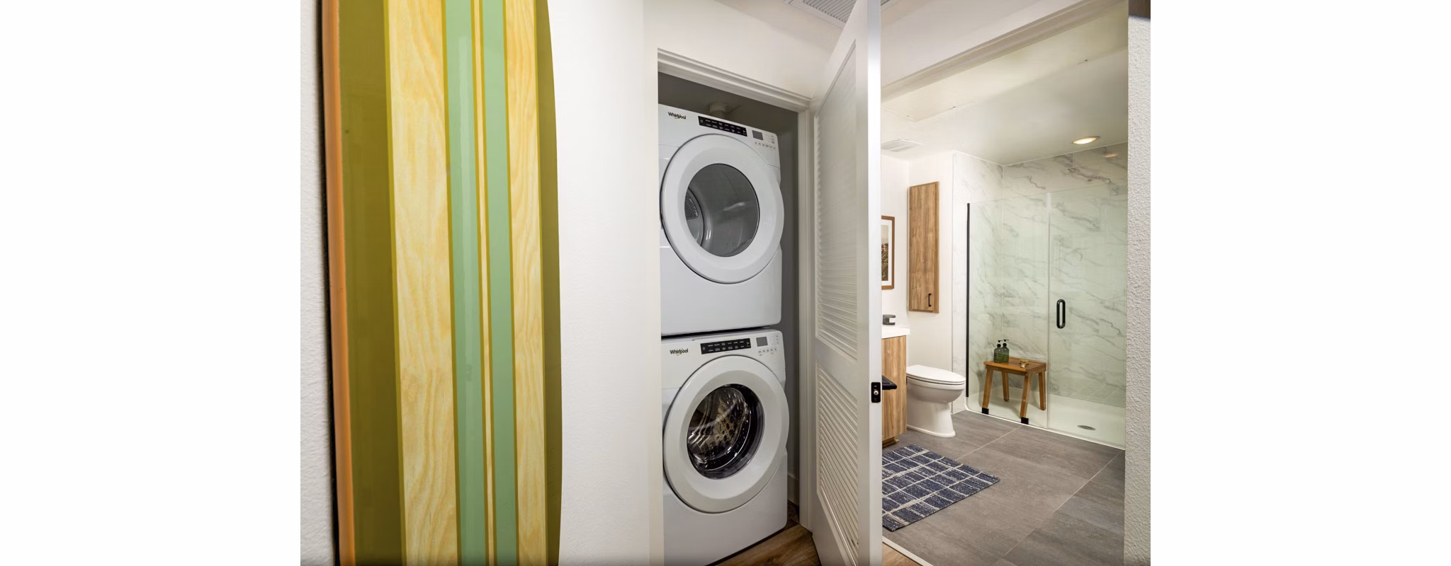 Laundry room with modern appliances and attached bathroom at Triton Encinitas Apartments