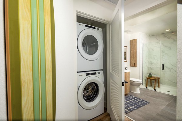 Laundry room with modern appliances and attached bathroom at Triton Encinitas Apartments