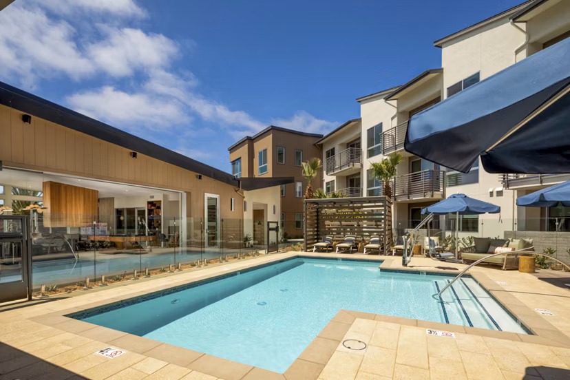 Resort-style pool at Triton Encinitas Apartments with lush landscaping and lounge areas