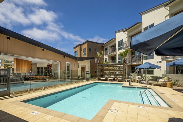 Resort-style pool at Triton Encinitas Apartments with lush landscaping and lounge areas