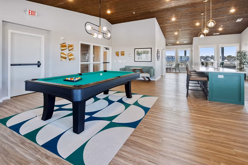 Clubhouse with modern lounge seating and entertainment area at Arasan Apartments, a luxury community by Greystar
