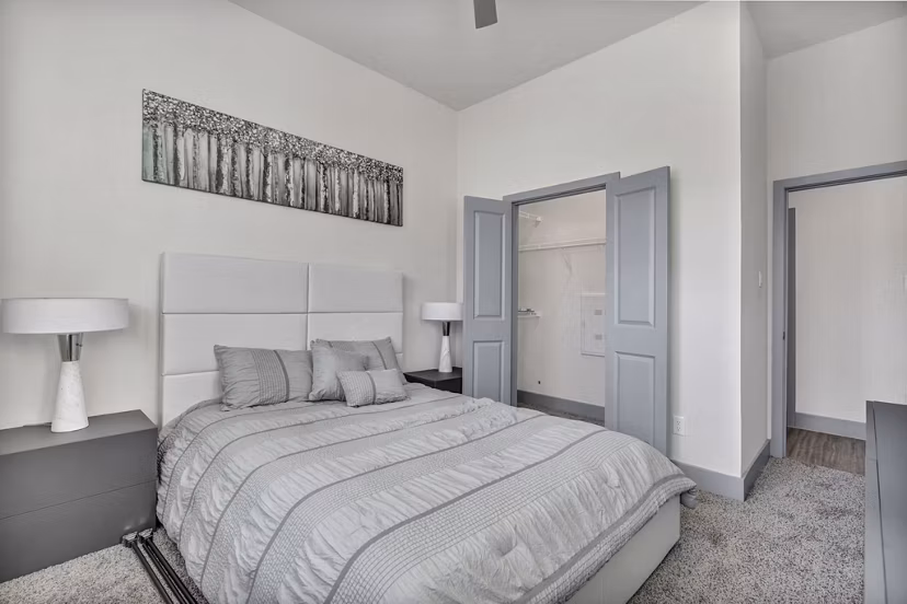 Spacious bedroom with modern decor in Preserve at Highway 6 Apartments, featuring a large window and comfortable bed setup