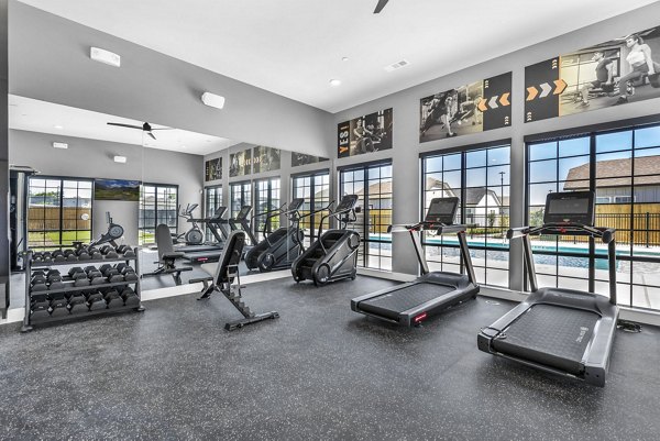 Fully-equipped fitness center at Preserve at Highway 6 Apartments with modern exercise machines and free weights