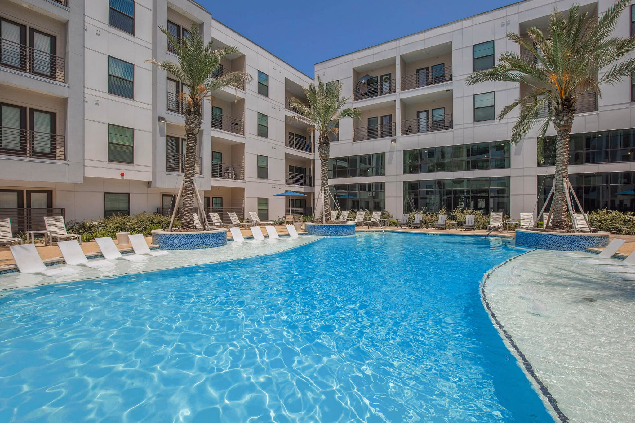 Resort-style pool at Vibe Med Center Apartments featuring lush landscaping and lounge seating, ideal for relaxation and community gatherings