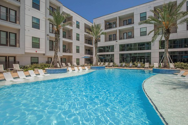 Resort-style pool at Vibe Med Center Apartments featuring lush landscaping and lounge seating, ideal for relaxation and community gatherings