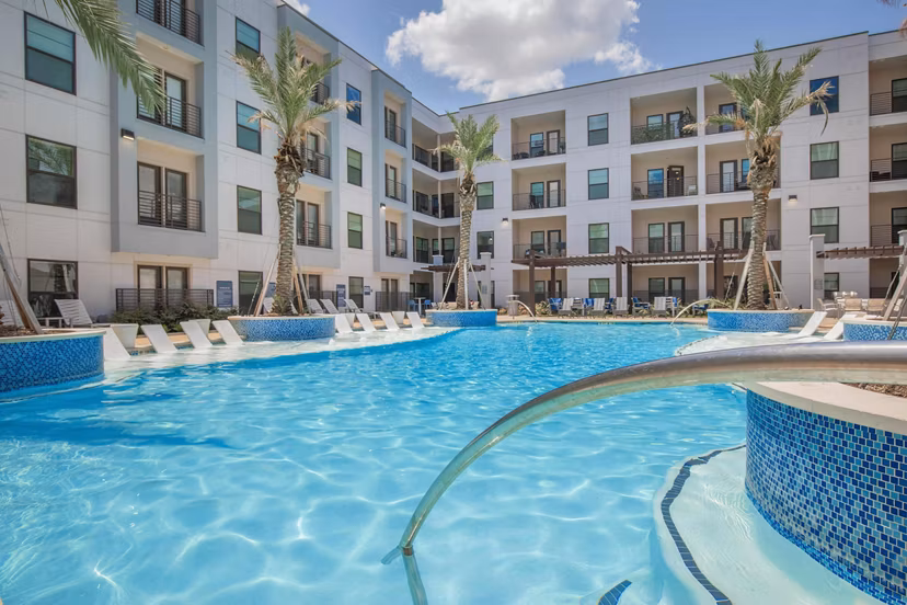Luxurious resort-style pool at Vibe Med Center Apartments featuring lush landscaping and comfortable lounging areas