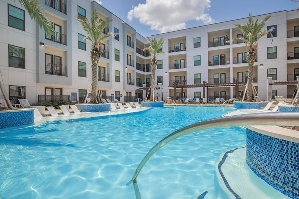 Luxurious resort-style pool at Vibe Med Center Apartments featuring lush landscaping and comfortable lounging areas