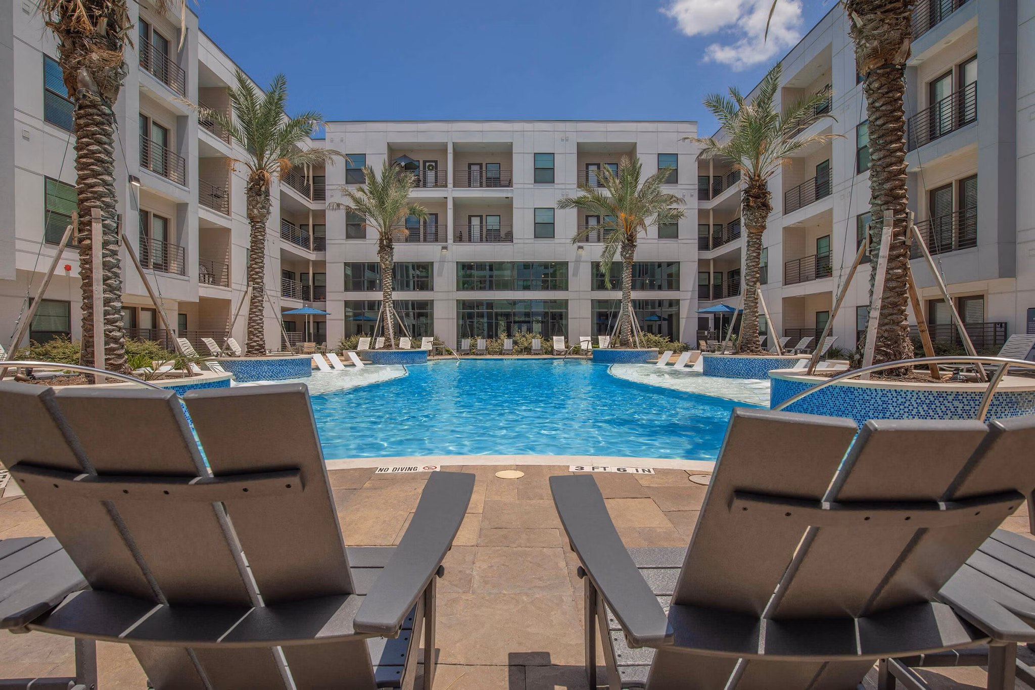 Resort-style swimming pool with lounge chairs at Vibe Med Center Apartments, offering a luxury retreat in urban living