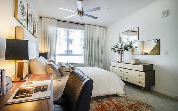 Bedroom featuring modern furnishings and large windows at MODA at Monrovia Station Apartments
