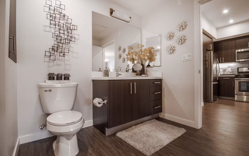 Modern bathroom with marble countertops and large mirror at MODA at Monrovia Station Apartments