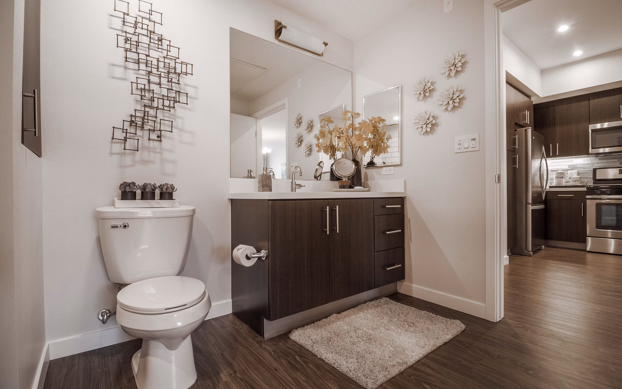 Modern bathroom with marble countertops and large mirror at MODA at Monrovia Station Apartments