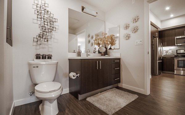 Modern bathroom with marble countertops and large mirror at MODA at Monrovia Station Apartments