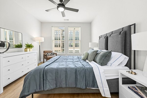 Cozy bedroom featuring modern decor and large windows at NOVEL Morrisville Apartments