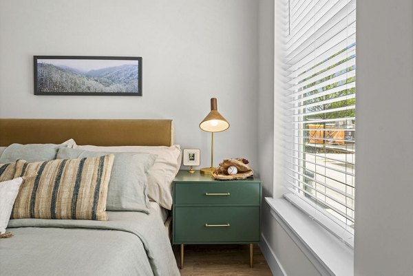 Cozy bedroom with modern furnishings at NOVEL Morrisville Apartments, highlighting warm tones and elegant lighting