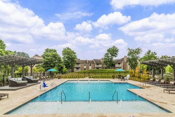 Relaxing poolside area featuring sun loungers and palm trees at Avana Matthews Apartments