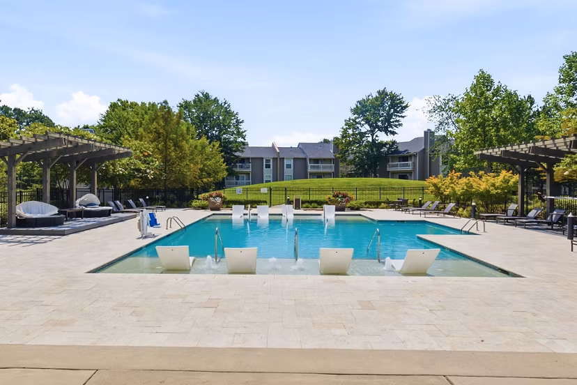 Resort-style pool area at Avana Matthews Apartments featuring sun loungers and lush landscaping