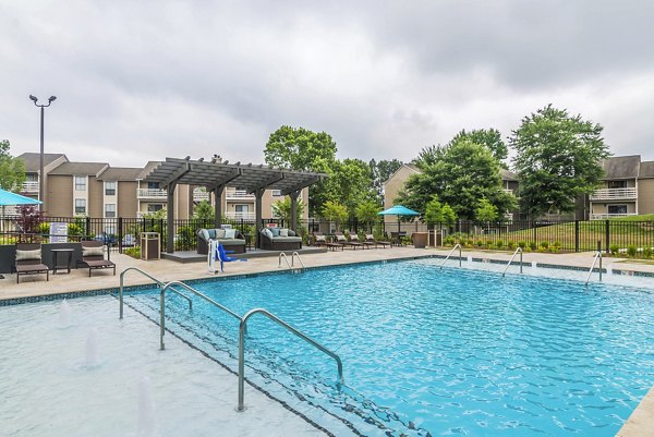 Resort-style pool area at Avana Matthews Apartments featuring sun loungers and lush landscaping