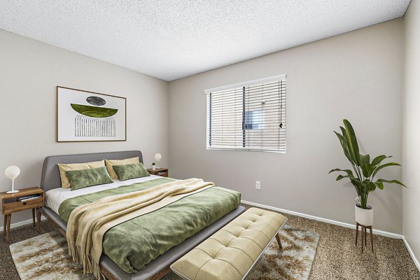 Modern bedroom with elegant decor in Coronado Palms Apartments, featuring cozy bedding and ample natural light