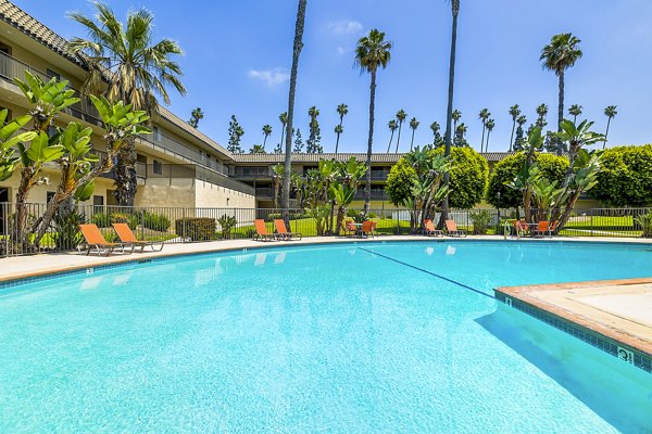Luxurious pool area with sun loungers at Coronado Palms Apartments, perfect for relaxation and leisurely swimming on sunny days