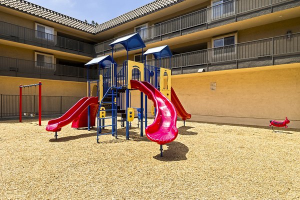 Colorful playground surrounded by lush greenery at Coronado Palms Apartments, offering a fun recreational area for families and children