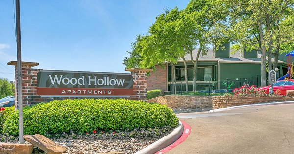 Wood Hollow Apartments: Modern signage amidst lush greenery