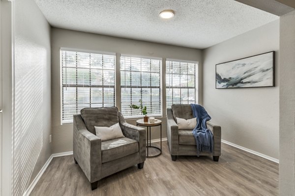 Modern living room with cozy seating and large windows in Wood Hollow Apartments
