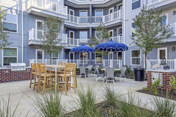 Outdoor grill area with seating at The Lacy at South Main Apartments, ideal for summer barbecues and social gatherings