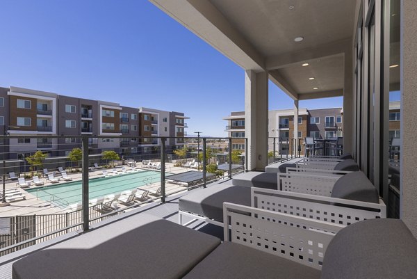 Spacious outdoor patio at Element 12 Cadence Apartments featuring cozy seating and view of lush landscape