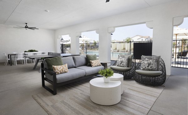 Outdoor patio area with sofa, chairs, and table overlooking a sparkling pool at luxury apartments