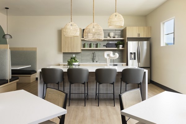 Modern kitchen and dining area featuring a central island, bar stools, and pendant lights in luxury apartments