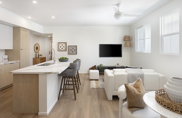 Open-concept living room and kitchen with island seating and modern decor in luxury apartments