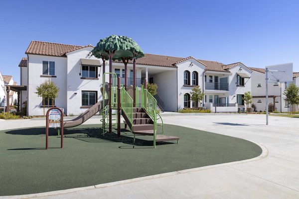 Playground with a slide and climbing structure at luxury apartments in a scenic outdoor area