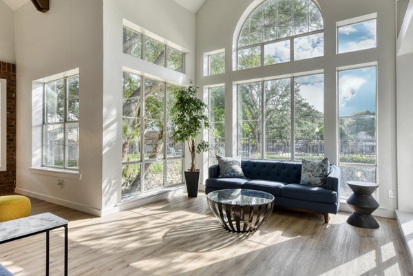 Living room with contemporary design and large windows in The Jax Apartments, showcasing urban luxury living