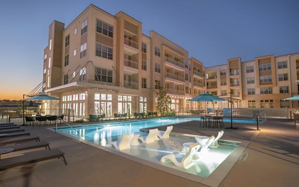 Relaxing outdoor pool area at Jovie Pflugerville Apartments, featuring lounge chairs and landscaping