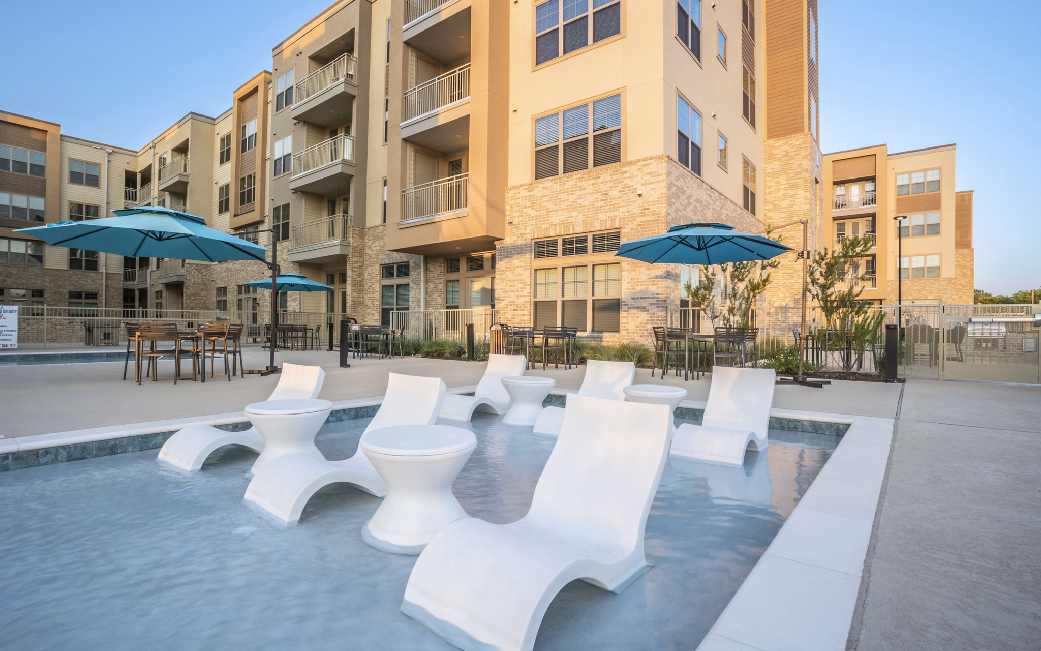 Outdoor pool area with lounge chairs at Jovie Pflugerville Apartments Enjoy luxury amenities and relaxation in a beautifully landscaped setting