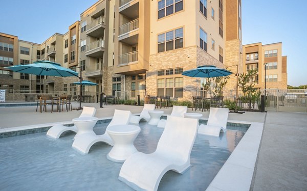 Outdoor pool area with lounge chairs at Jovie Pflugerville Apartments Enjoy luxury amenities and relaxation in a beautifully landscaped setting