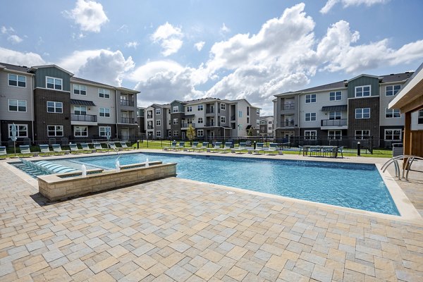 Resort-style swimming pool at Prose Greenbriar Apartments with sun loungers and palm trees enhancing the luxury living experience