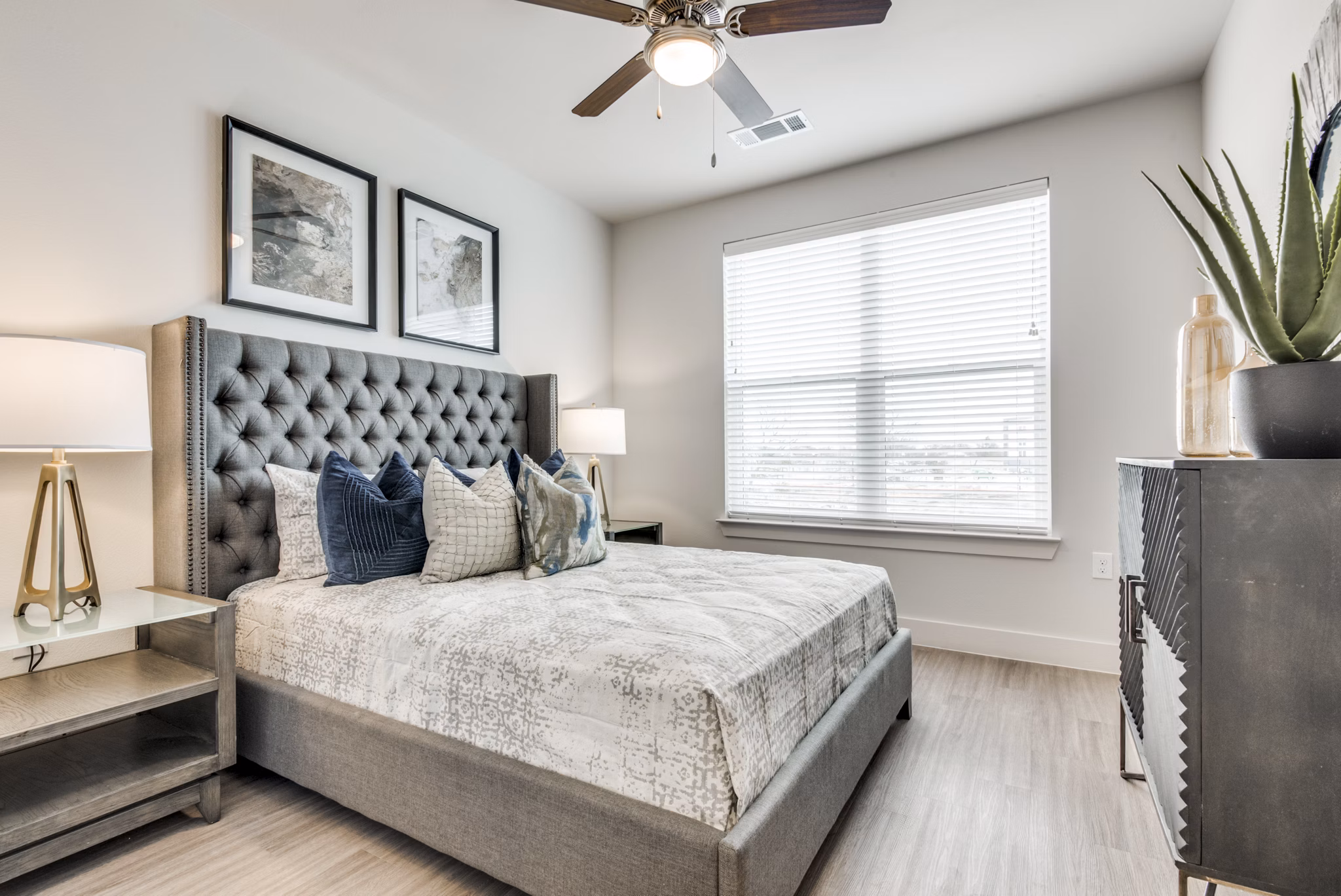 Modern bedroom featuring elegant decor and large windows at The District in Little Elm Apartments