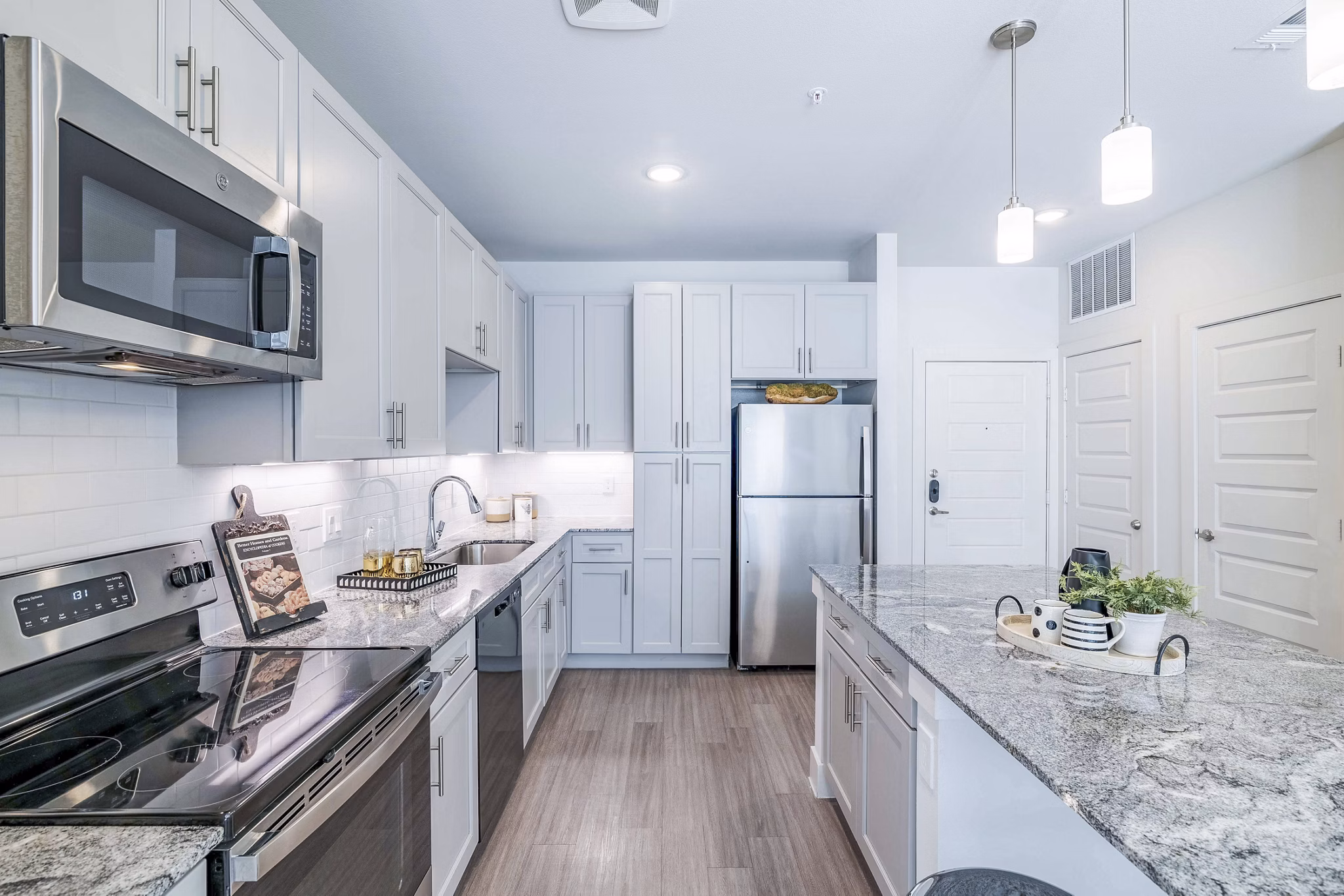 Modern kitchen with stainless steel appliances and granite countertops at The District in Little Elm Apartments
