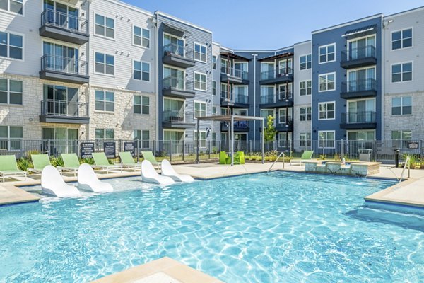 Inviting pool surrounded by lounge chairs at The District in Little Elm Apartments, perfect for relaxation and recreation